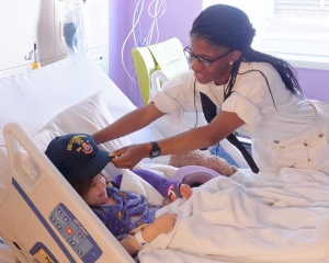 160422-N-NW169-002 SAN ANTONIO (April 22, 2016) Gunner’s Mate Seaman Johnelle Jones, assigned to USS Constitution, presents a Navy command ball cap to a patient at Children's Hospital of San Antonio during a Caps for Kids visit. The Sailors from Old Ironsides are participating in San Antonio’s Navy Week. The Navy Week program is designed to raise awareness about the Navy in areas across the country that traditionally do not have a naval presence, and to bring America's Navy closer to the people it protects through community relations projects, speaking engagements, science, technology, engineering, mathematics (STEM) demonstrations and media interviews with flag hosts and local area Sailors. (U.S. Navy photo by Chief Mass Communication Specialist Michael O’Day/Released)